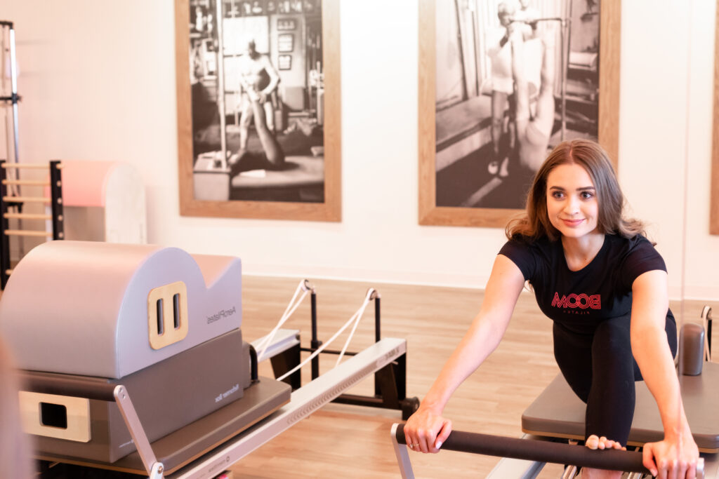 smiling woman on pilates reformer using the footbar for a pilates reformer exercise