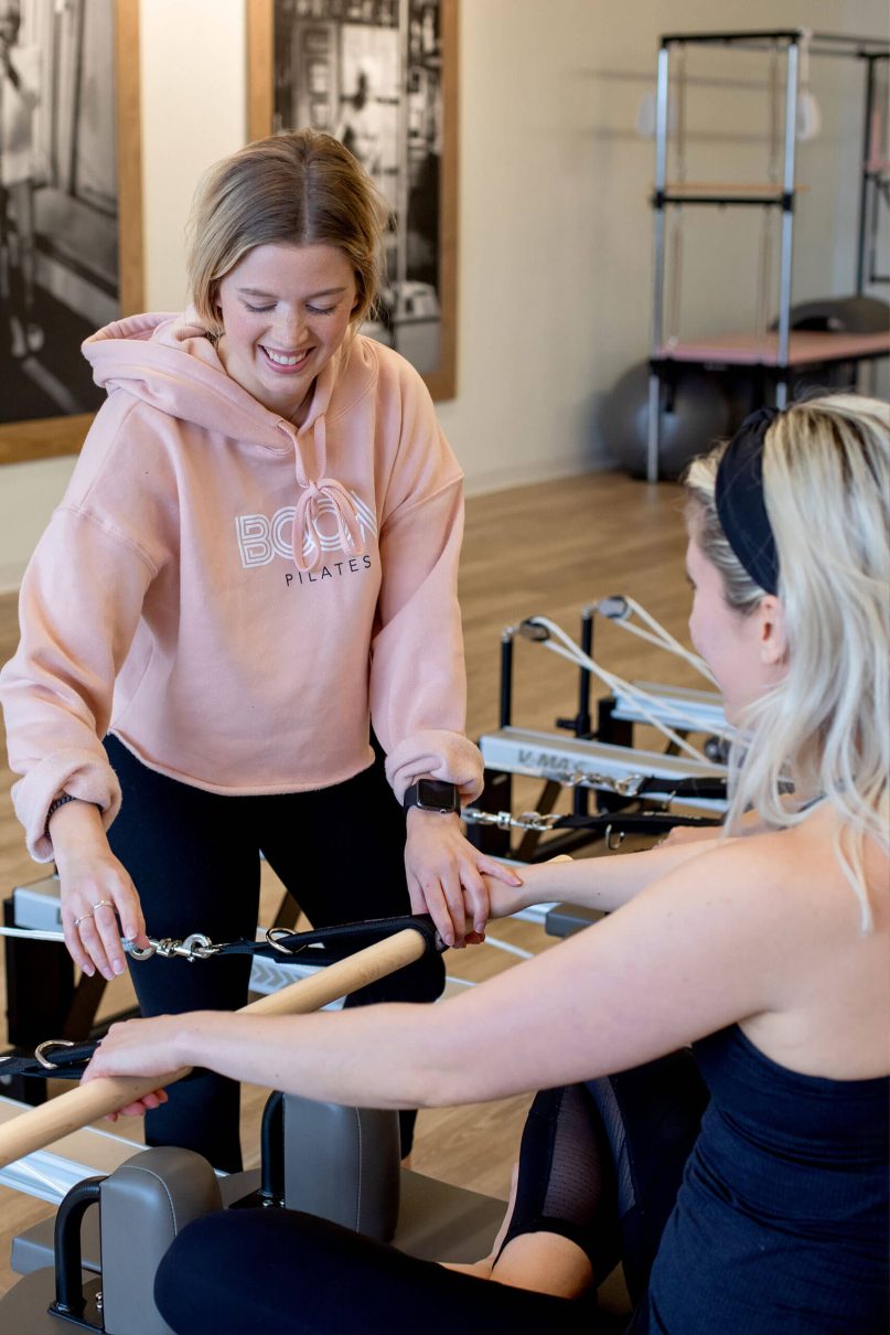 Pilates instructor helping a student with their form